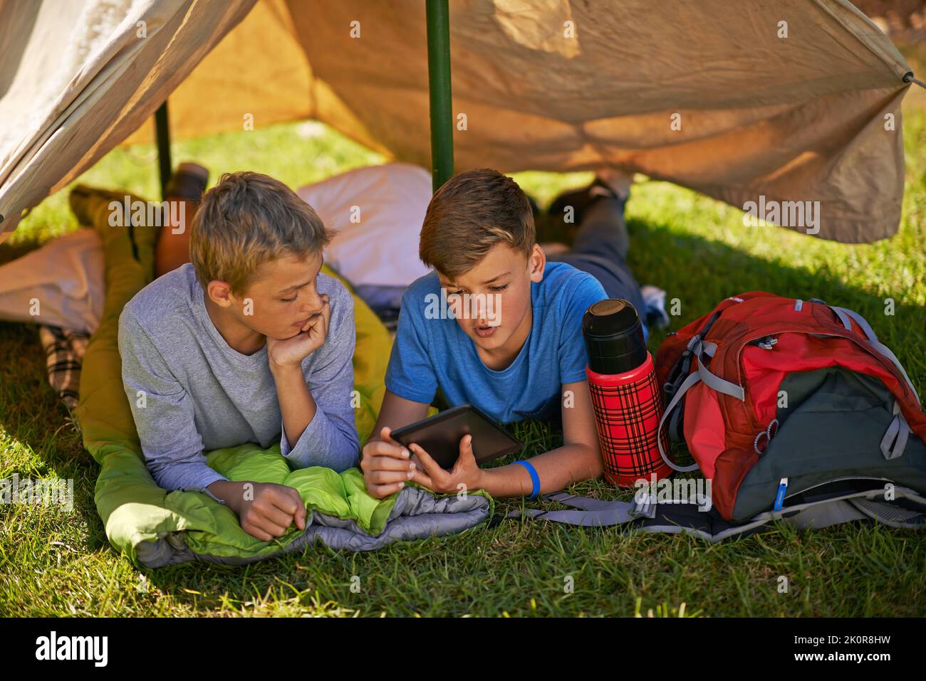 Sieh dir das an, bro. Ein kleiner Junge, der seinem Freund etwas auf einem digitalen Tablet zeigt, während er auf dem Campingplatz ist. Stockfoto