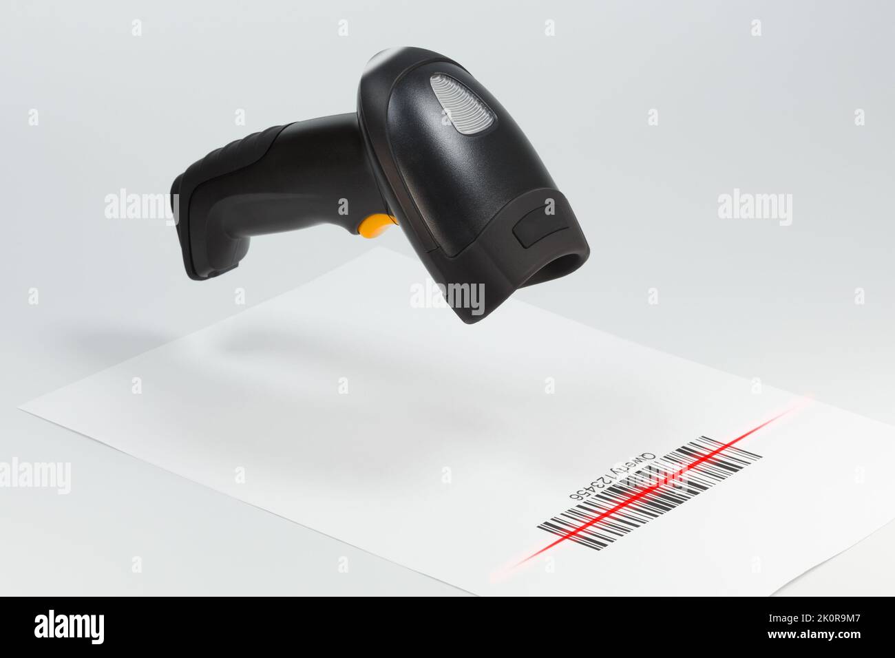 Schwarzer Barcodescanner scannt einen Barcode auf einer weißen Seite.automatisierte Informationsverarbeitung Stockfoto