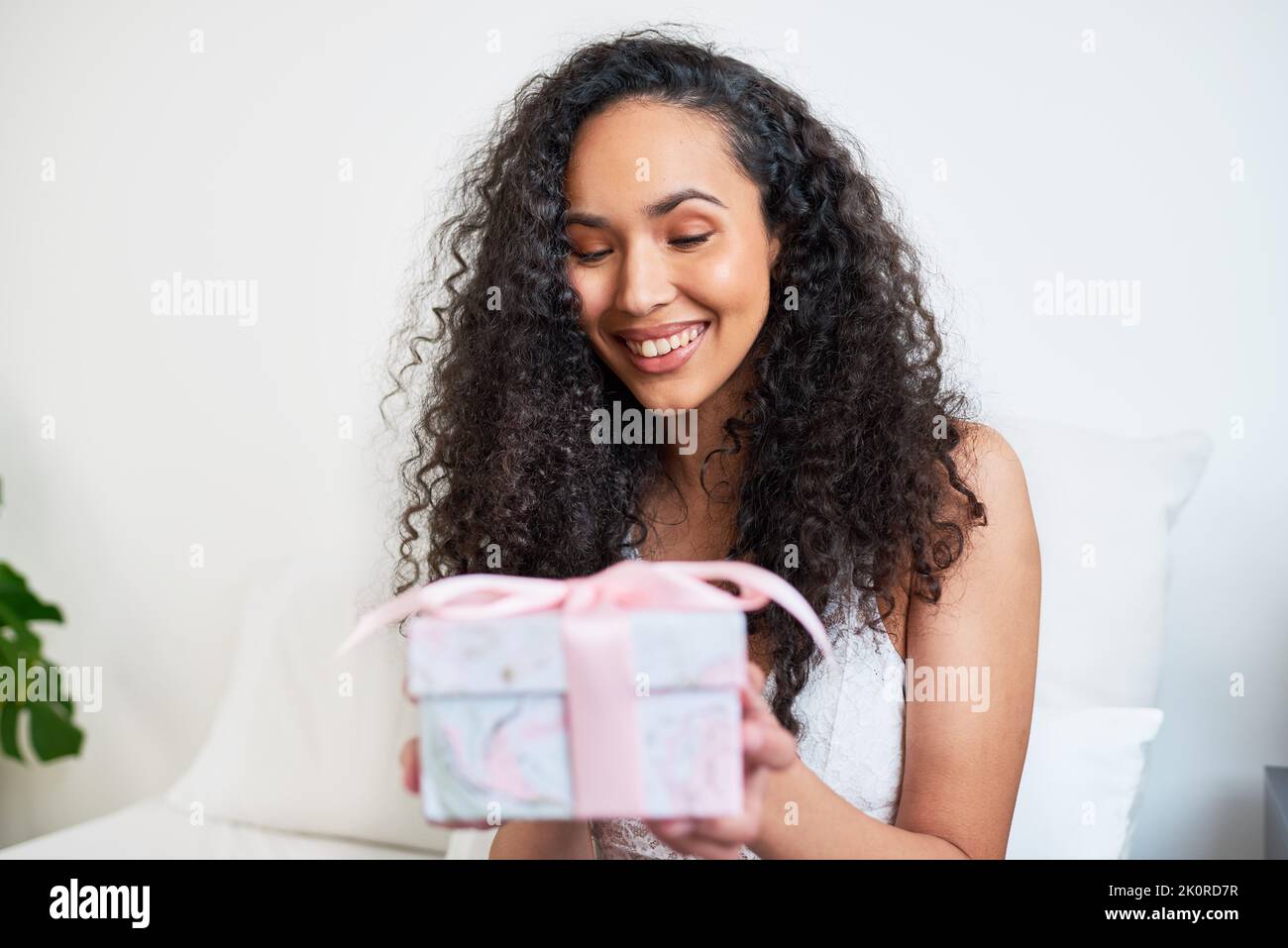 Eine schöne junge Frau erhält ein Geschenk im Bett für besondere Anlässe Stockfoto