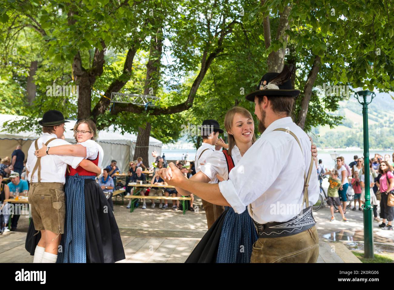 Junge Männer und Frauen tanzen in Tirol Kostüme bei einem Festmahl im Park von Zell am See in Österreich Stockfoto