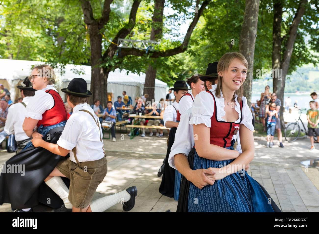 Junge Männer und Frauen tanzen in Tirol Kostüme bei einem Festmahl im Park in Zell am See, Österreich Stockfoto