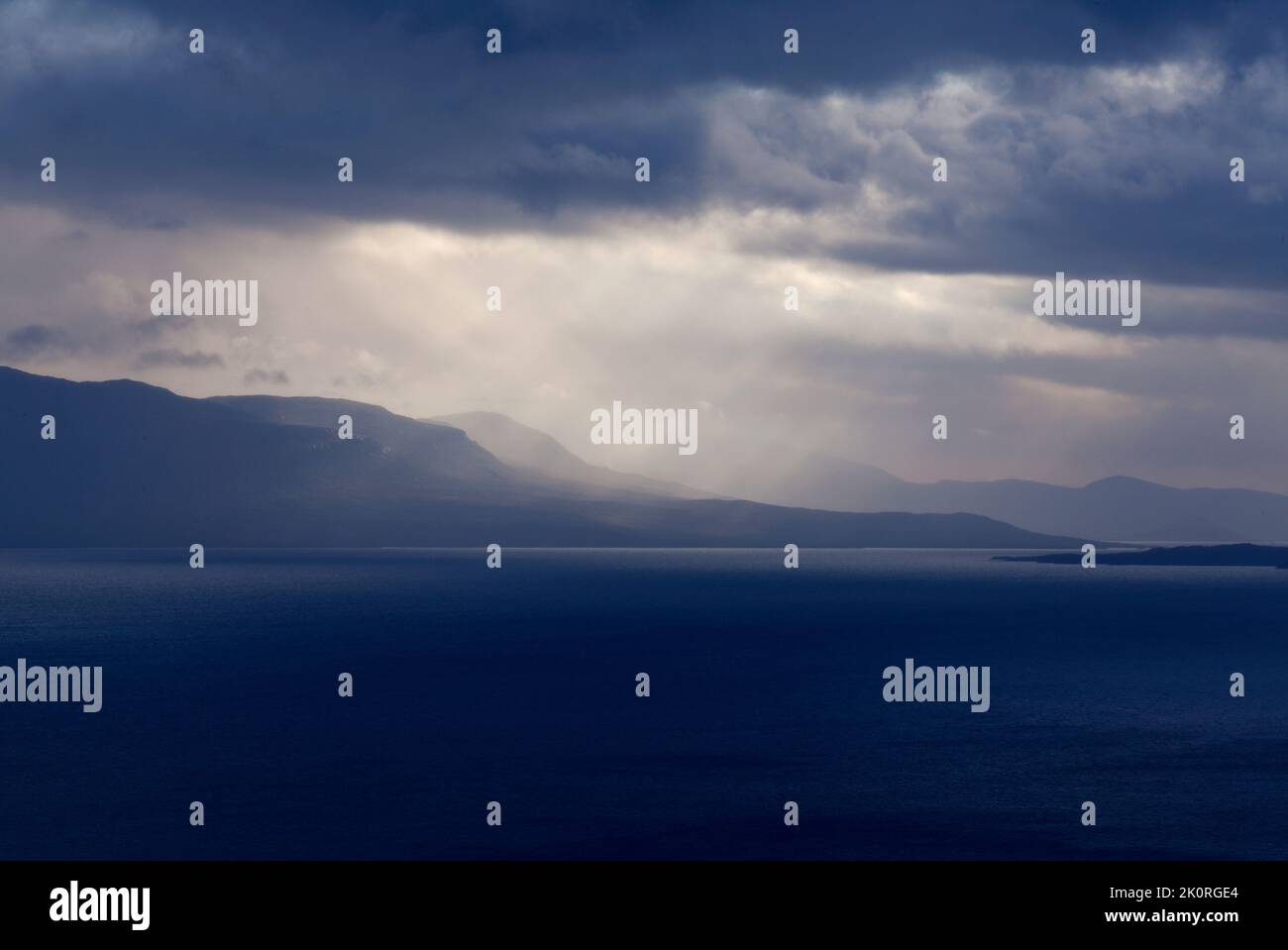 September und Sonnenstrahlen passieren regnerische Wolken. See auf dieser Seite und Berg im Hintergrund. Stockfoto