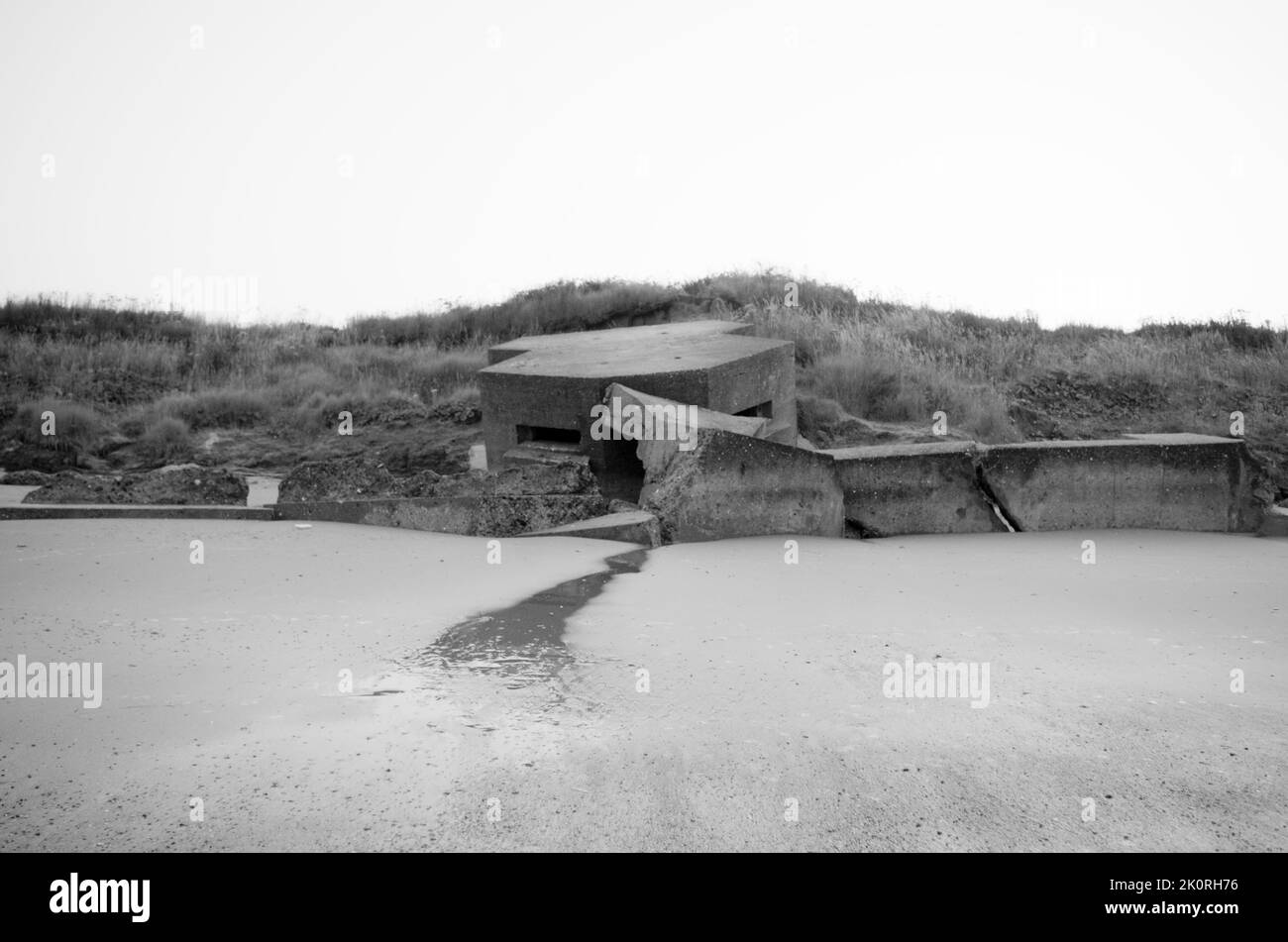 Eingestürzter Pillbox aus dem Zweiten Weltkrieg an der Küste. Monochrom. Stockfoto