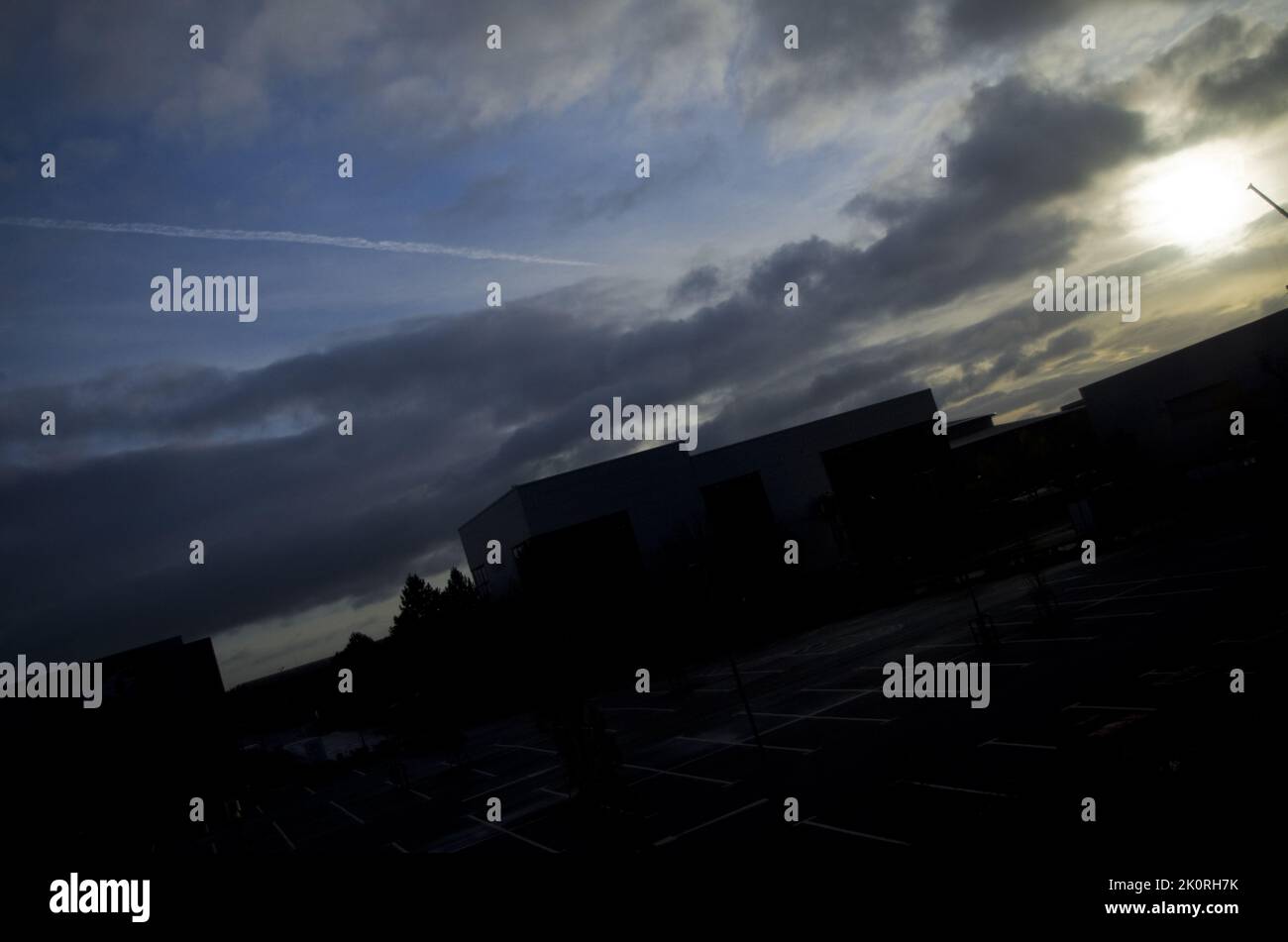 Dramatischer blauer Himmel bei Sonnenaufgang mit Wolken über der silhouettierten Industrielandschaft. Stockfoto
