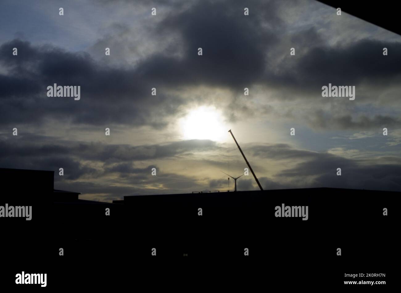 Dramatischer blauer Himmel bei Sonnenaufgang mit Wolken über der silhouettierten Industrielandschaft. Stockfoto