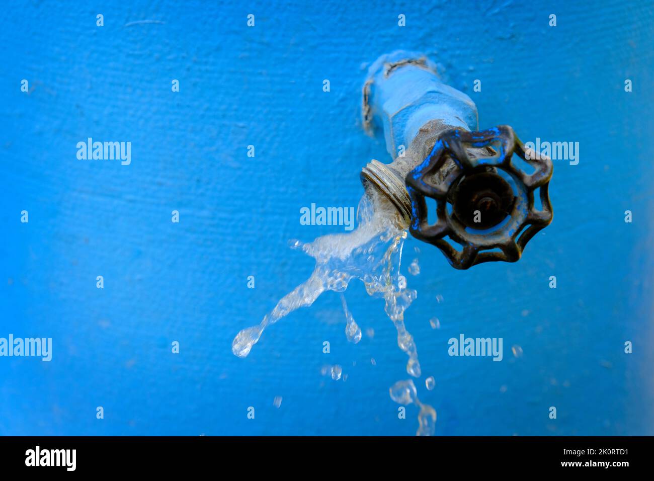 Wasserhähne sprühen kühles Wasser fließt mit Tropfen blau Stockfoto