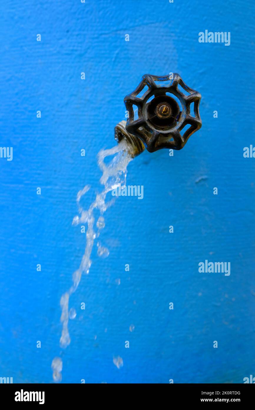 Wasserhähne sprühen kühles Wasser fließt mit Tropfen blau Stockfoto