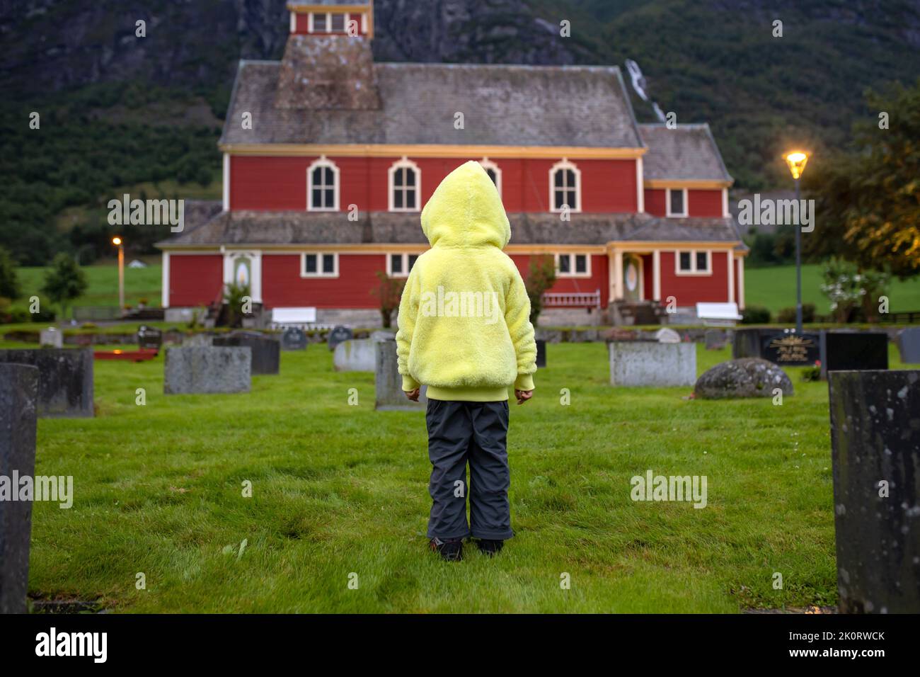 Trauriges kleines Kind, blonder Junge, im Regen auf dem Friedhof stehend, traurige Person, trauernd Stockfoto