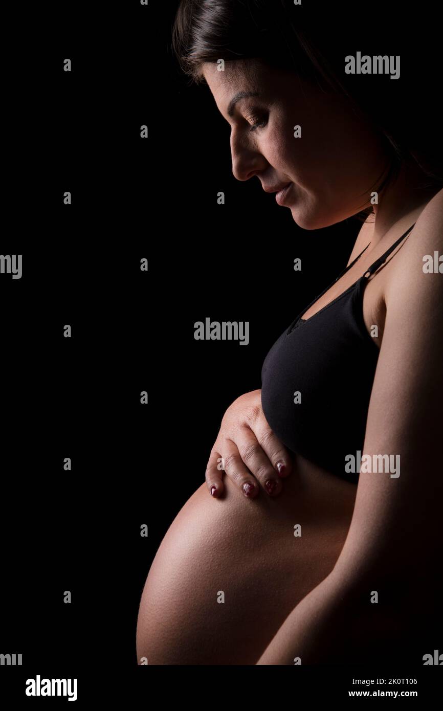 Junge Brünette Frau schaut hinunter auf ihr Baby Beule. Stockfoto