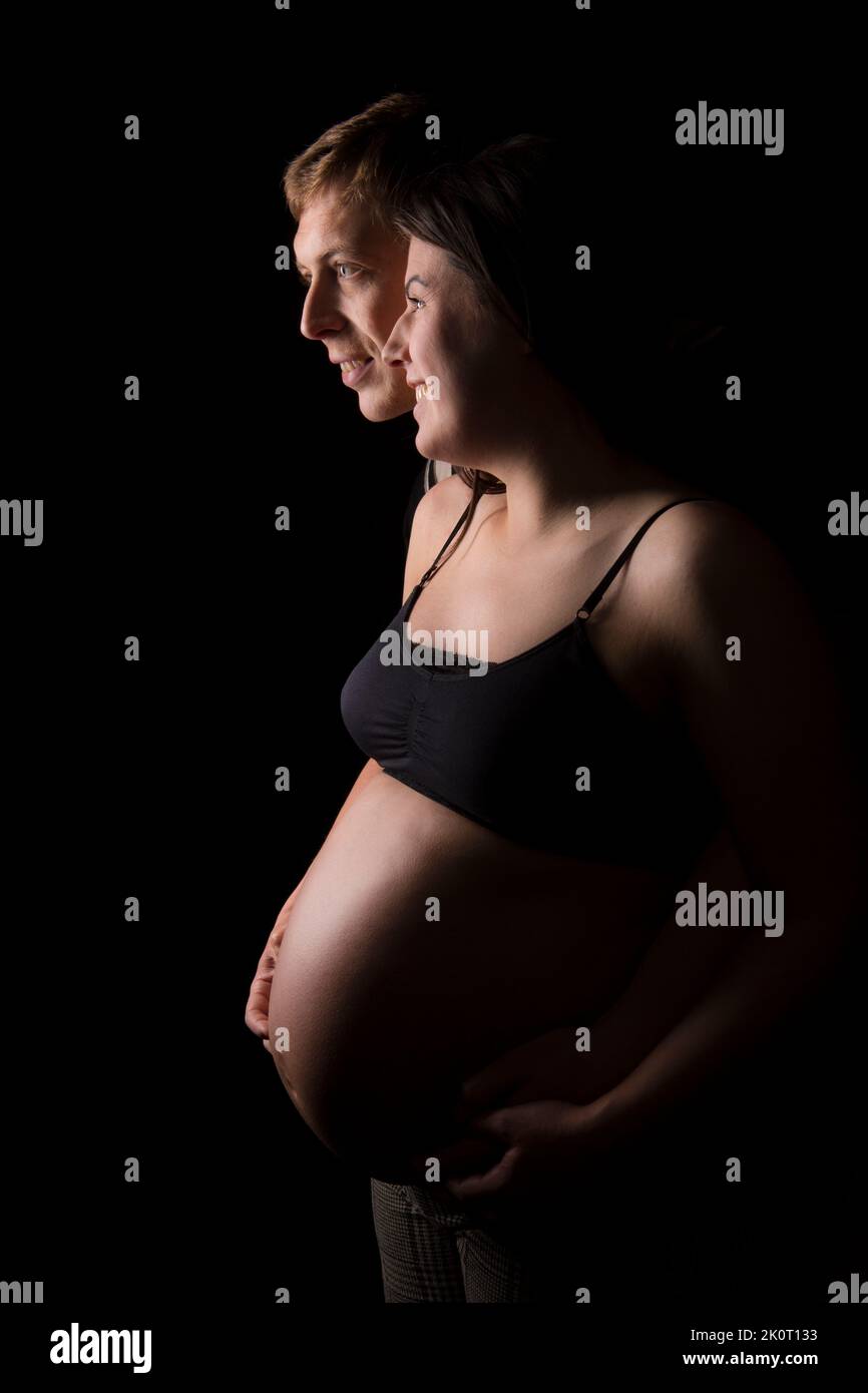 Mutter und Vater werden Seite Pose zusammen und halten Mütter Baby Beule Stockfoto