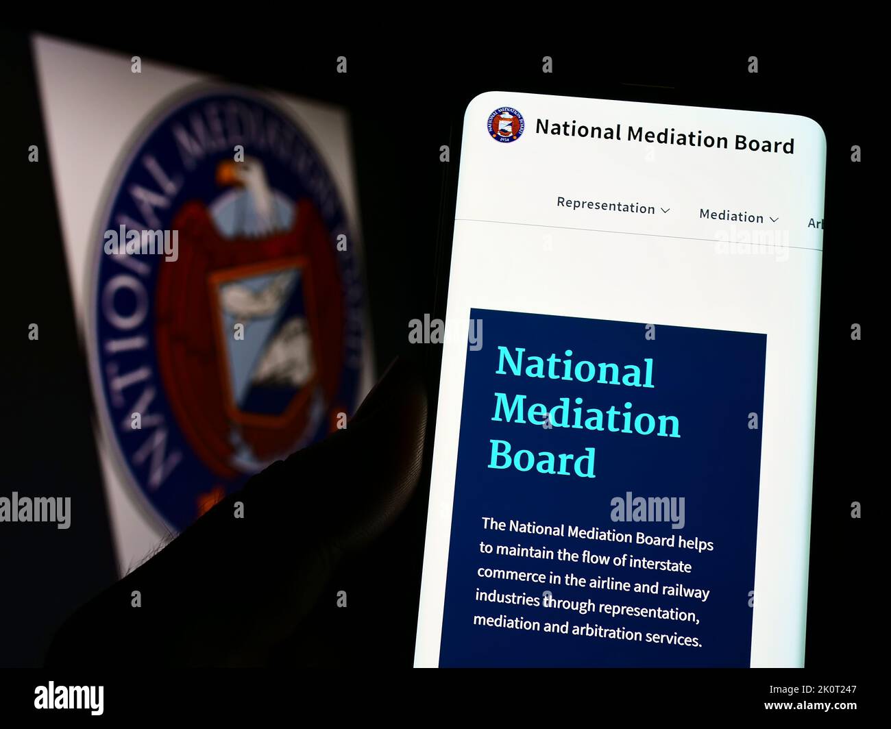 Person, die Mobiltelefon mit der Website der US-Agentur National Mediation Board (NMB) auf dem Bildschirm vor dem Logo hält. Konzentrieren Sie sich auf die Mitte des Telefondisplays. Stockfoto