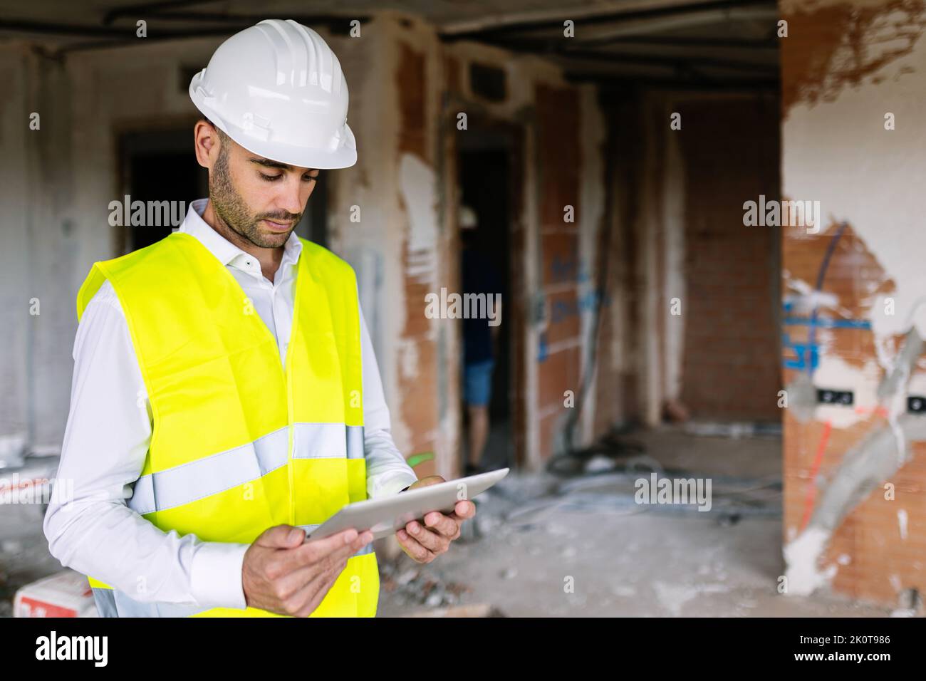 Junger erwachsener Architekt auf der Baustelle, der an einem digitalen Tablet arbeitet Stockfoto