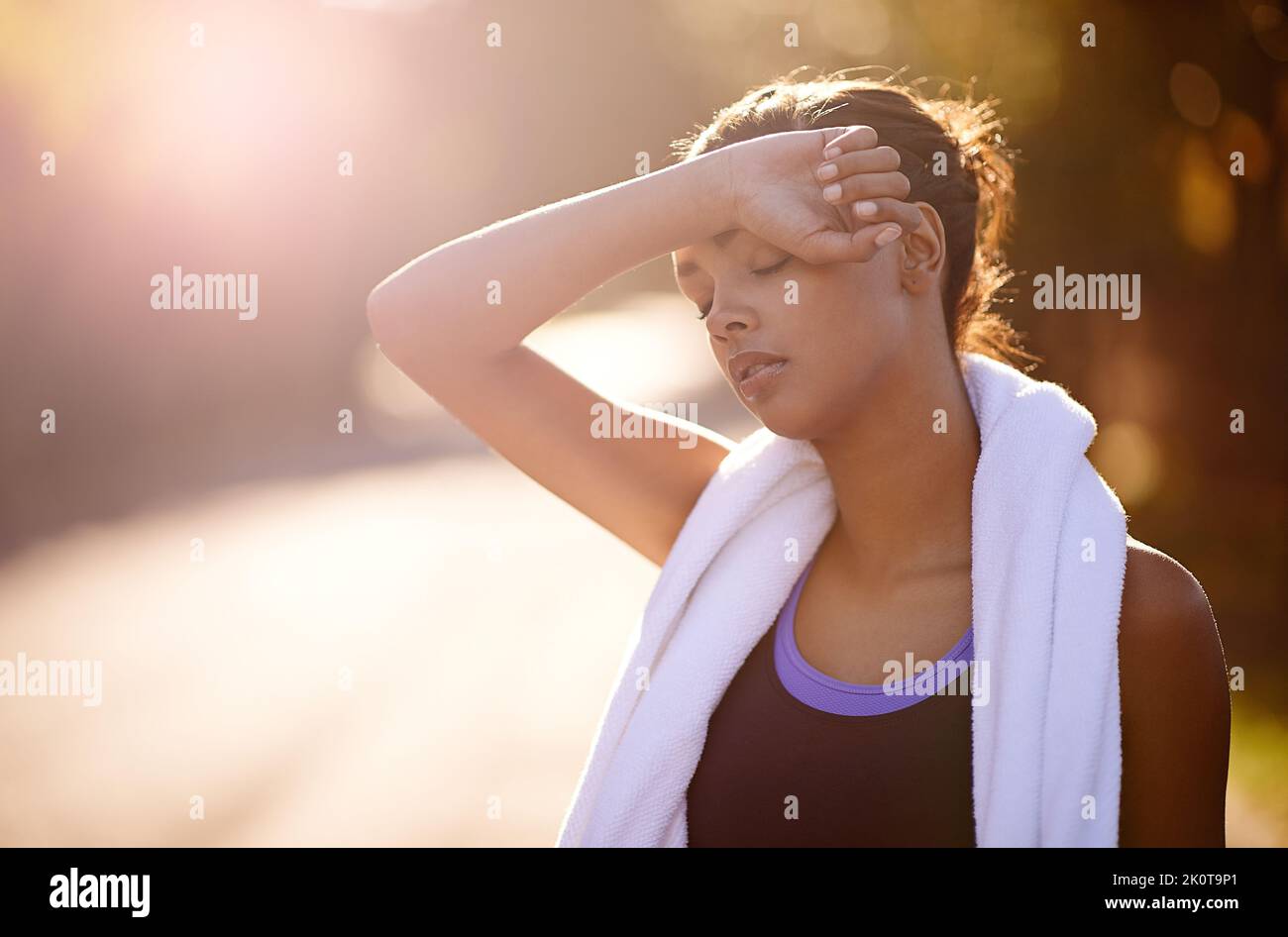 Gute Dinge kommen zu denen, die schwitzen. Eine Frau, die nach einem intensiven Training im Freien den Schweiß abwischt. Stockfoto