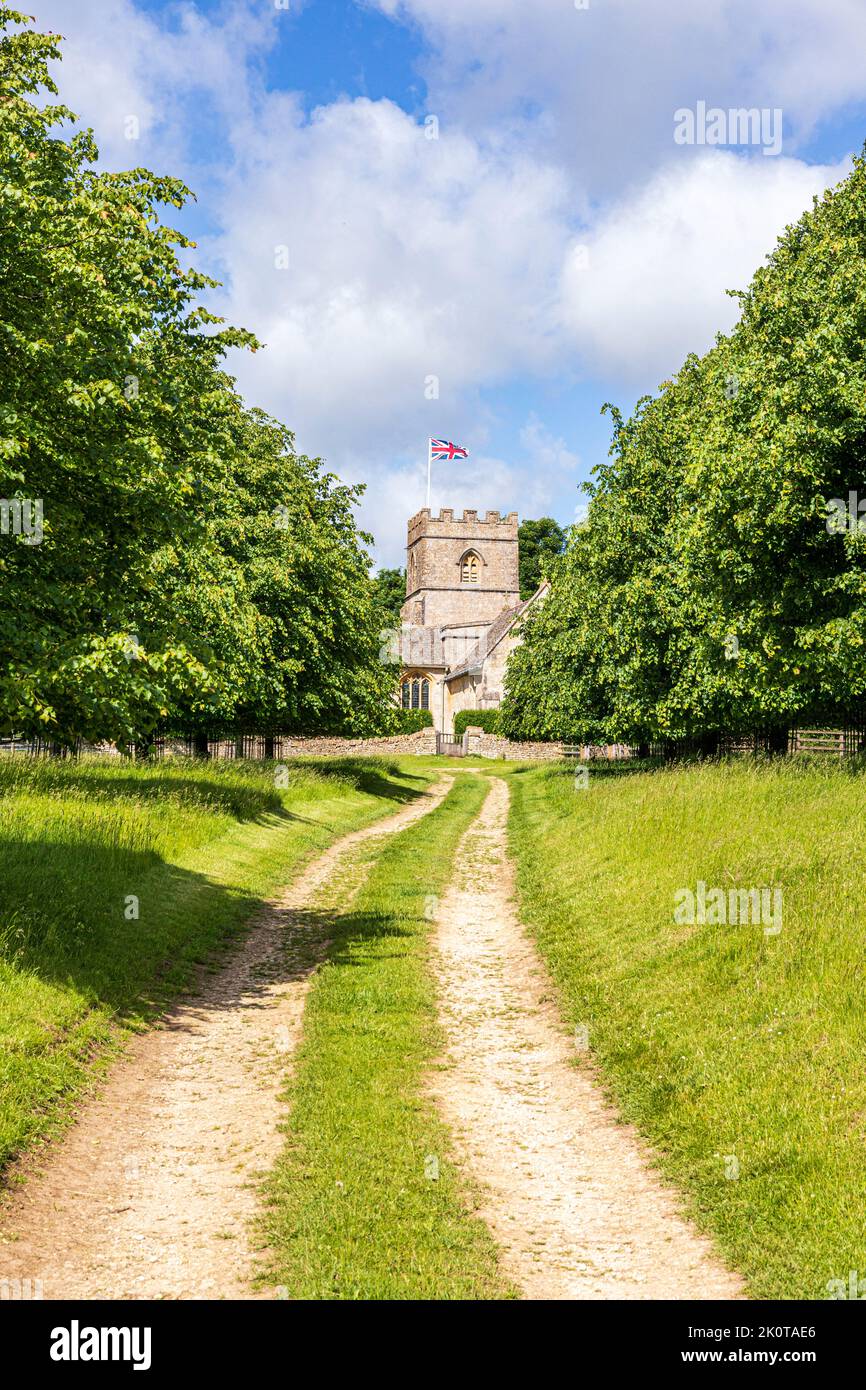 Eine Allee von Bäumen auf beiden Seiten des Tracks, die zur normannischen Kirche St. Michael und All Angels im Cotswold-Dorf Guiting Power, Glouce, führt Stockfoto