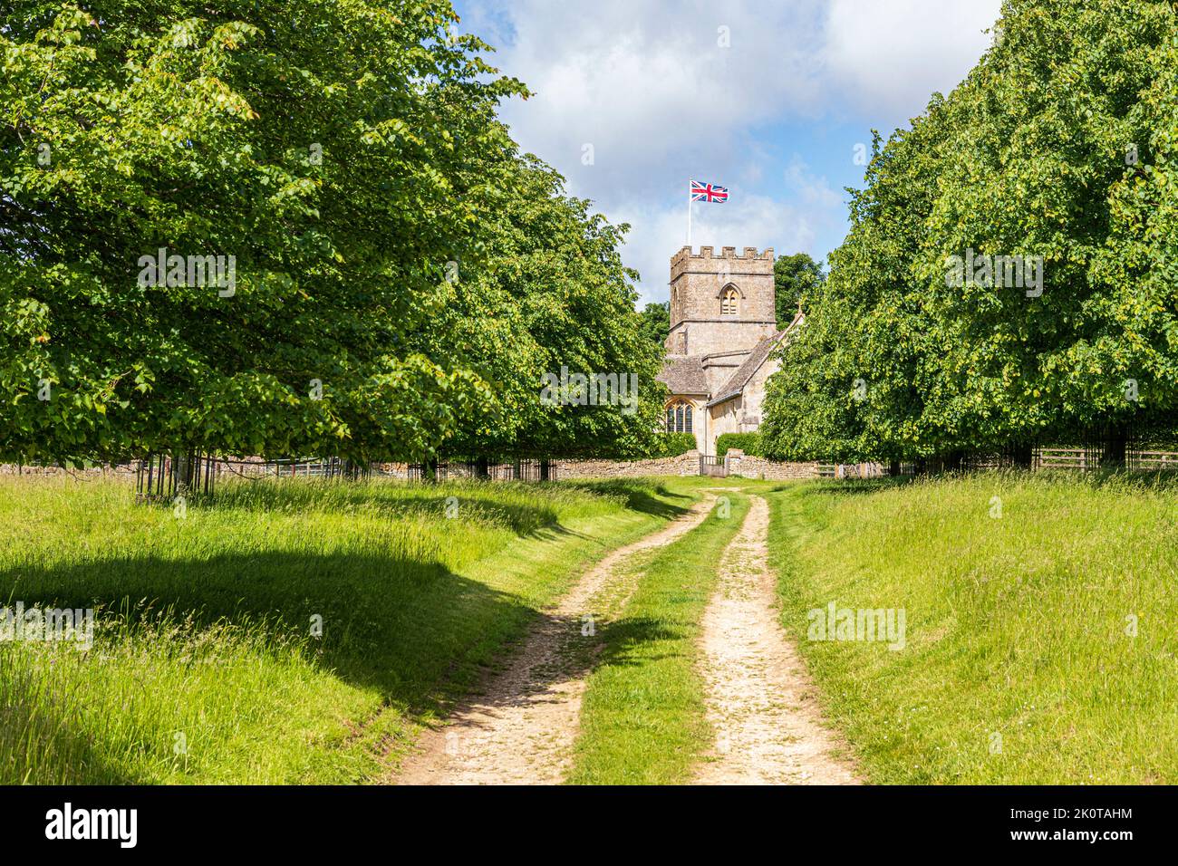 Eine Allee mit Bäumen an der Strecke, die zur normannischen Kirche St. Michael and All Angels im Dorf Guiting Power in Cotswold, Gloucestershire UK führt Stockfoto