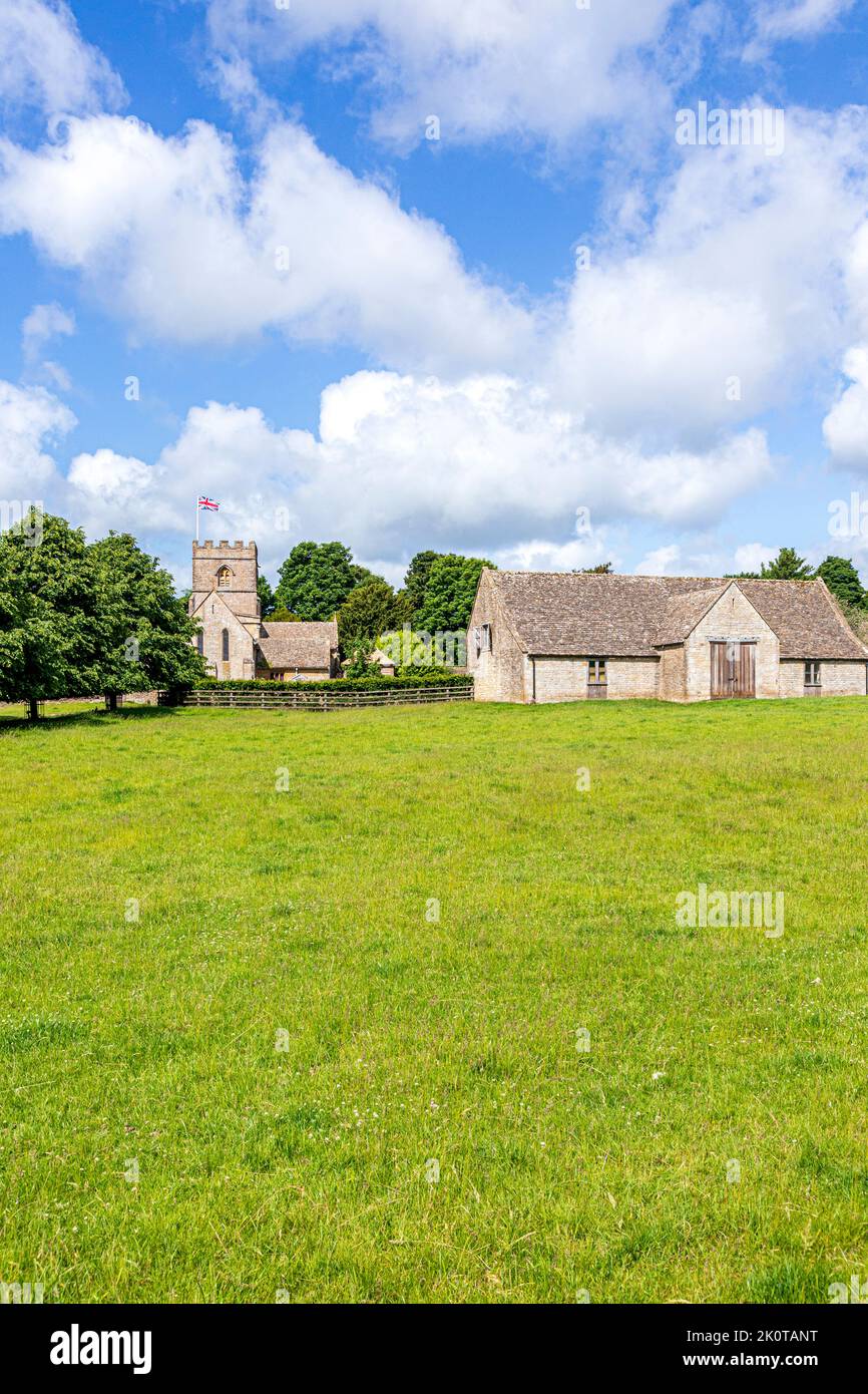 Die normannische Kirche St. Michael and All Angels und eine Scheune aus dem 18.. Jahrhundert im Cotswold-Dorf Guiting Power, Gloucestershire, Großbritannien Stockfoto
