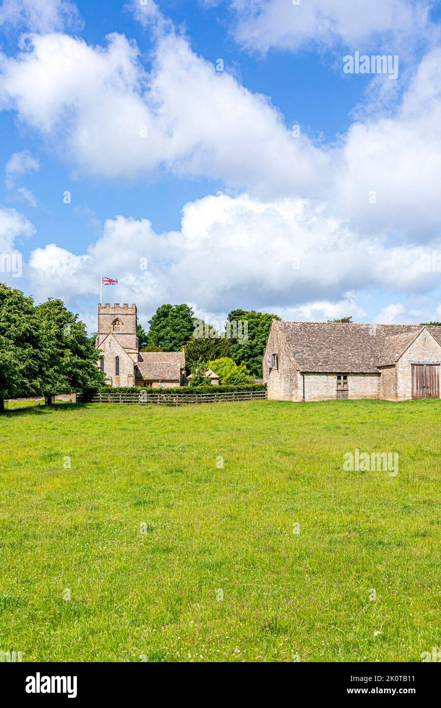 Die normannische Kirche St. Michael and All Angels und eine Scheune aus dem 18.. Jahrhundert im Cotswold-Dorf Guiting Power, Gloucestershire, Großbritannien Stockfoto