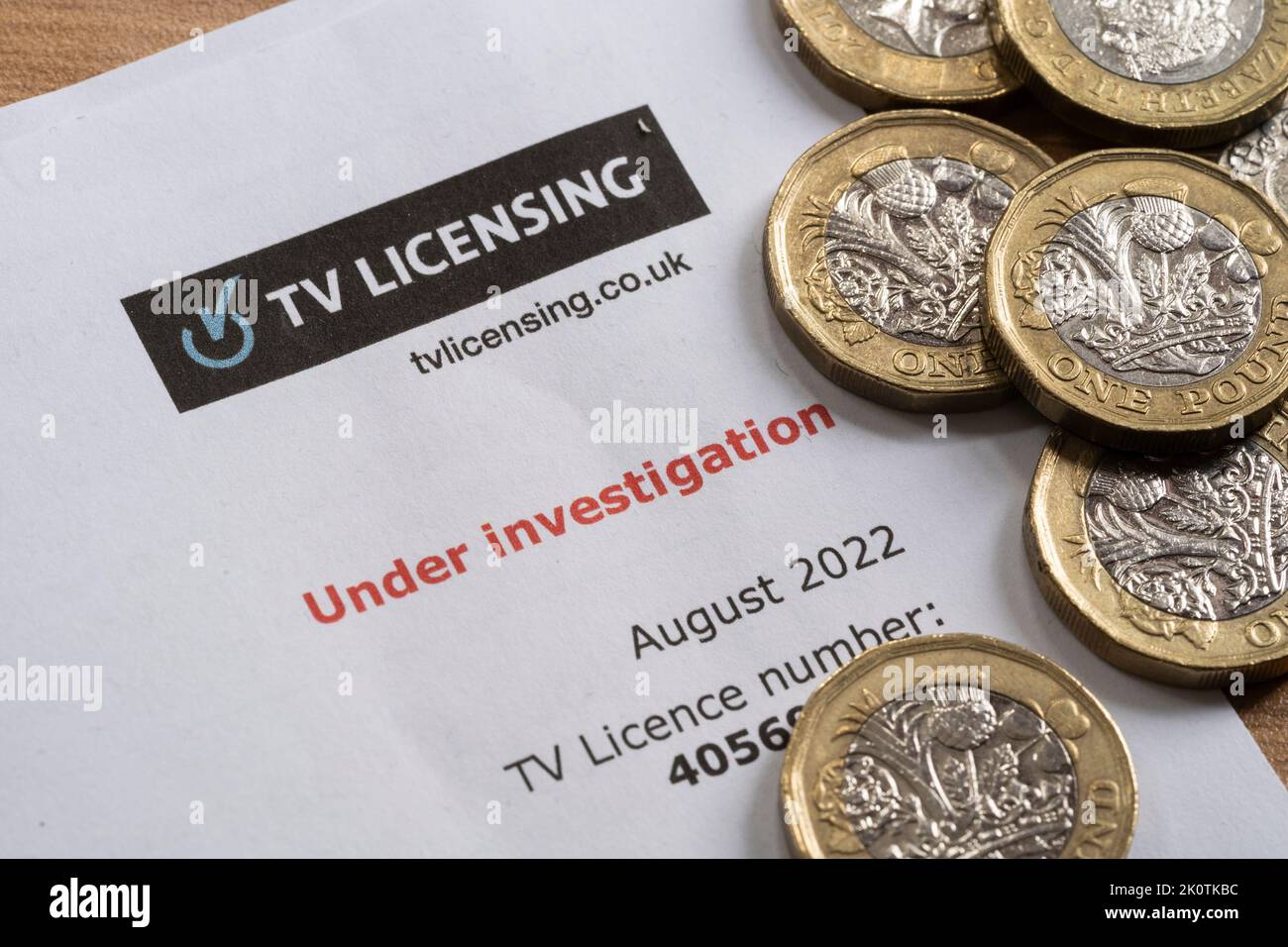 Untersuchungsschreiben wegen verspäteter/nicht-Zahlung der BBC-TV-Lizenzgebühr mit Münzen. Die Lizenzgebühr und die Finanzierung durch die BBC sind zunehmend bedroht Stockfoto