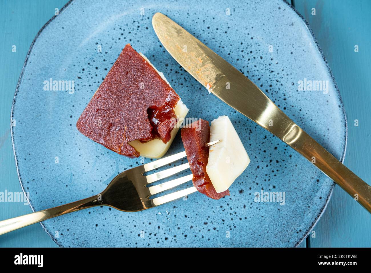 Nahaufnahme einer goldenen Gabel mit Stücken von Guava-Süße und Käse auf einem Teller. Stockfoto