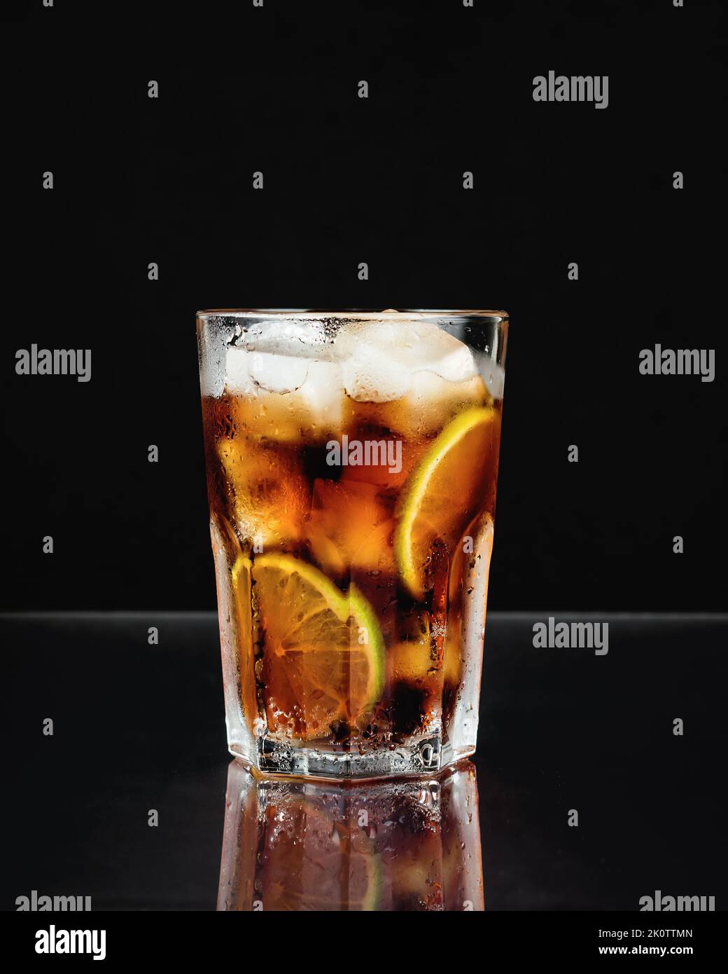 Cuba Libre Cocktail mit Limette auf schwarzem Hintergrund. Stockfoto