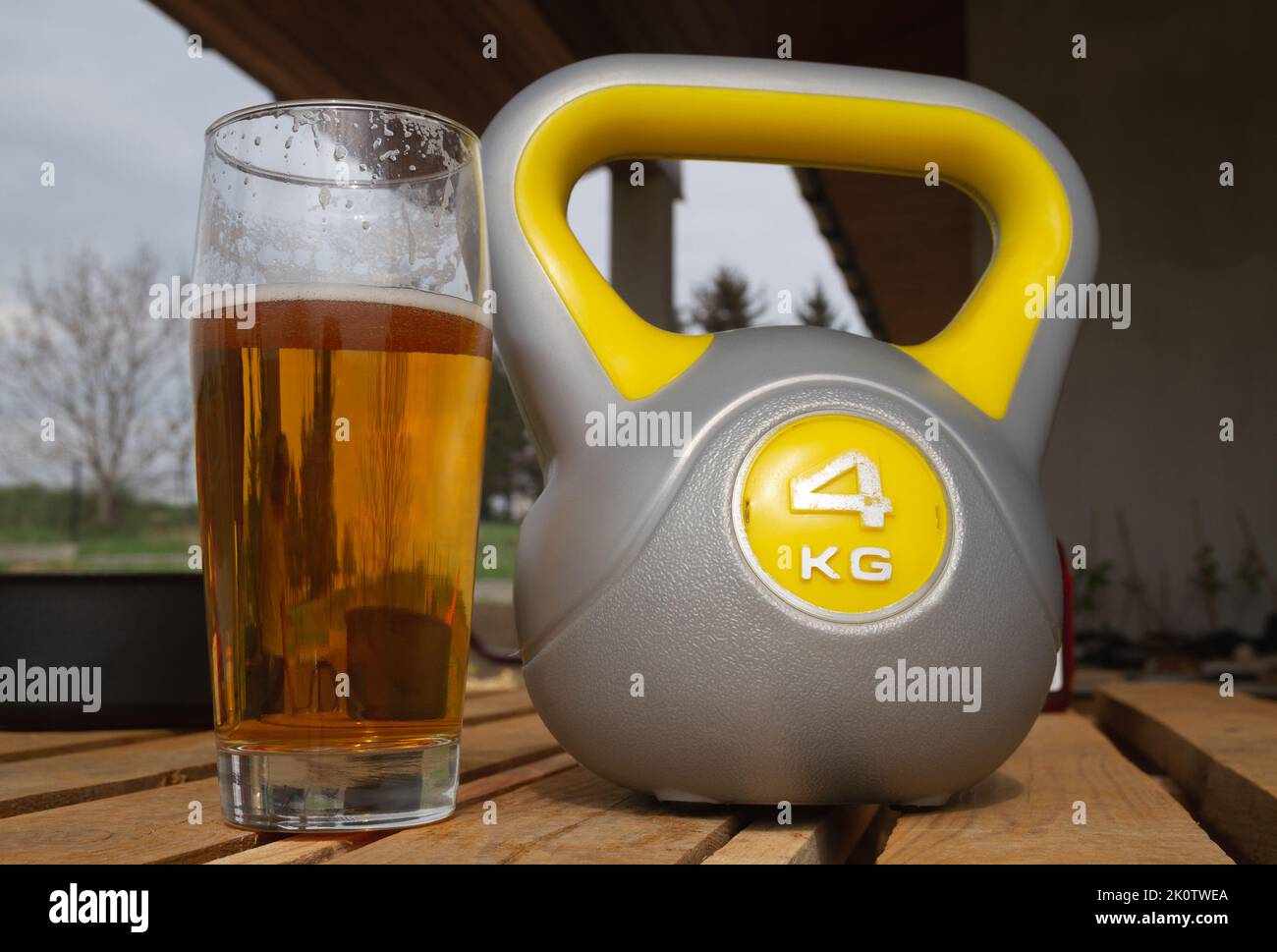 Fitnessraum mit Kugelhantel und ein Glas Bier. Alkoholkontrast mit Sport, Wahl zwischen gesundem oder schädlichem Lebensstil. Stockfoto