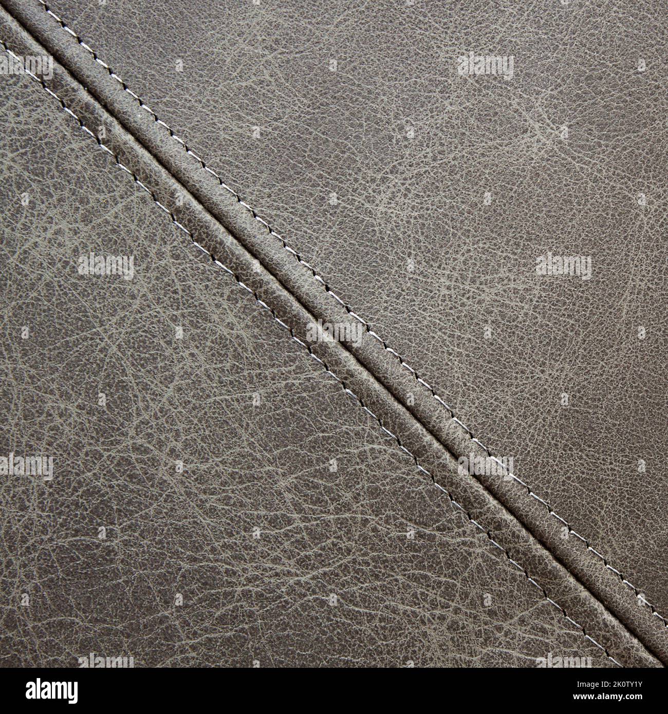 Graues Leder mit einer diagonalen Ziernaht, Hintergrund aus Nahaufnahme Stockfoto