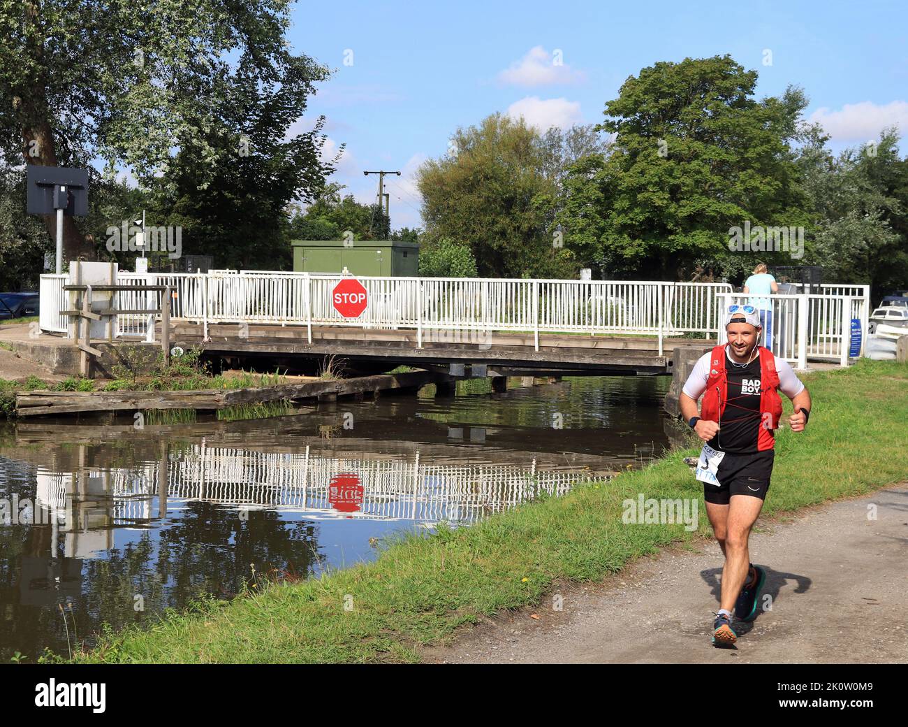 Ein lächelnder Läufer passiert die Swing Bridge der Crabtree Lane und nimmt an einem sonnigen Augusttag am langen Kanalrennen 2022 von Liverpool nach Leeds Teil. Stockfoto