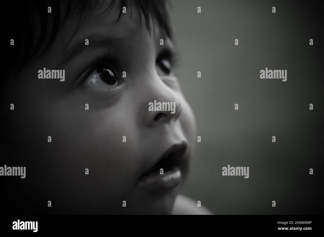 Nahaufnahme einer monochromen Schwarzweißaufnahme eines Latino-Babys, das verwundert nach oben blickt Stockfoto