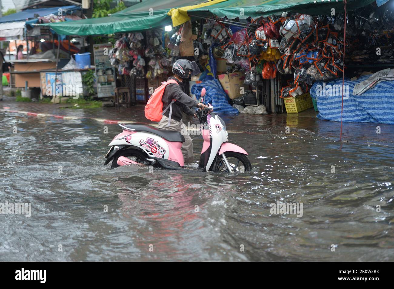 Bangkok, Thailand. 13. September 2022. Eine Person mit einem Motorrad wat am 13. September 2022 in Bangkok, Thailand, durch das Flutwasser. Die Bangkok Metropolitan Administration (BMA) warnte am Dienstag vor moderaten bis starken Regenfällen und potenziellen Überschwemmungen von 4 bis 11 Uhr Ortszeit in den 12 Bezirken der thailändischen Hauptstadt. Dies geschah, nachdem mehrere Teile der Stadt nach schweren Monsunregen in den letzten Tagen überschwemmt worden waren. Quelle: Rachen Sageamsak/Xinhua/Alamy Live News Stockfoto