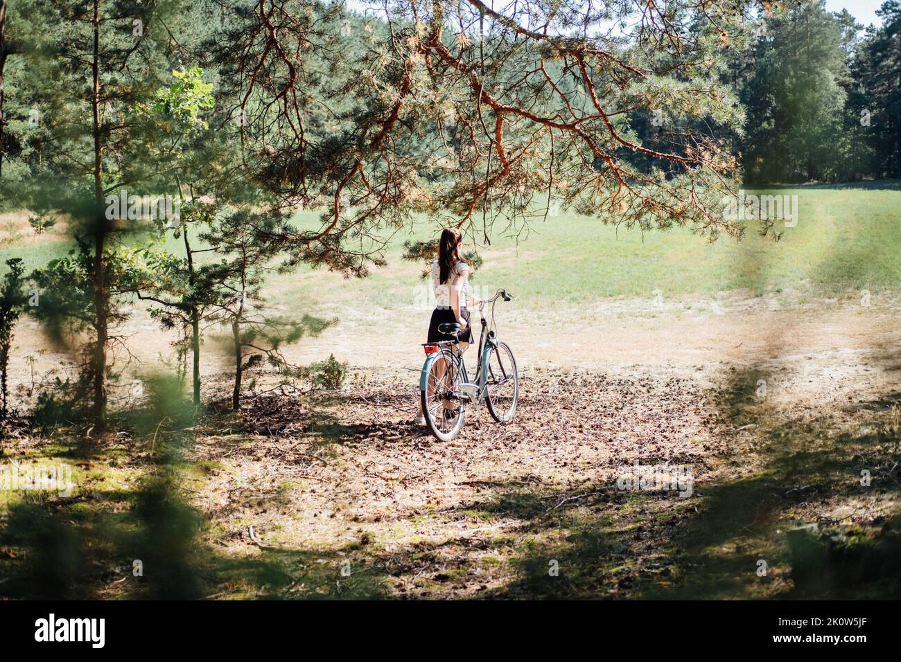 Psychische Gesundheit Vorteile des Radfahrens, reduzieren Angst. Radfahren im Wald. Fahrradwege Im Wald. Alleinerziehende Frau, die an sonnigen Tagen Fahrrad im Kiefernwald reitet. Stockfoto