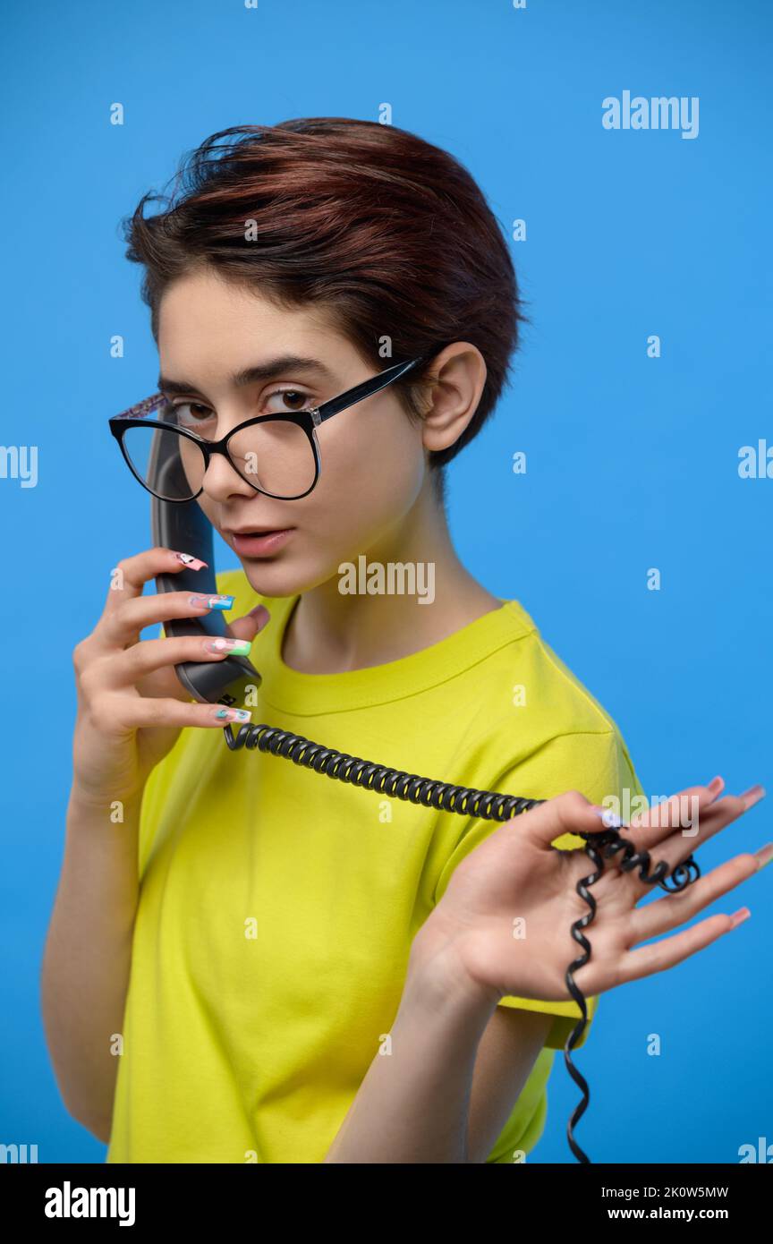 Schöne junge dünne Brünette leise im Gespräch auf einem Festnetztelefon Stockfoto