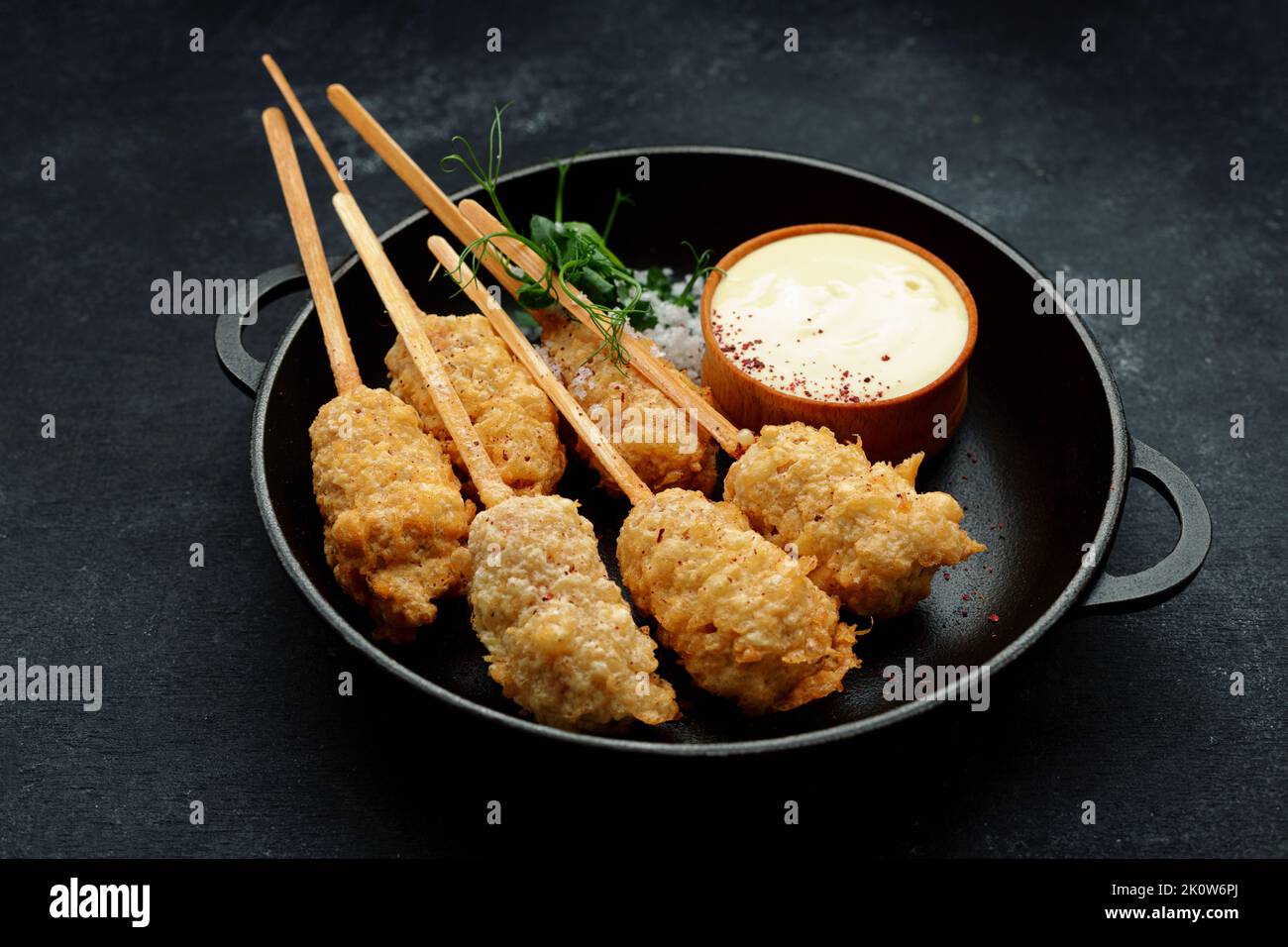 Tempura Garnelen auf einem Holzstock in einer schwarzen Pfanne Stockfoto