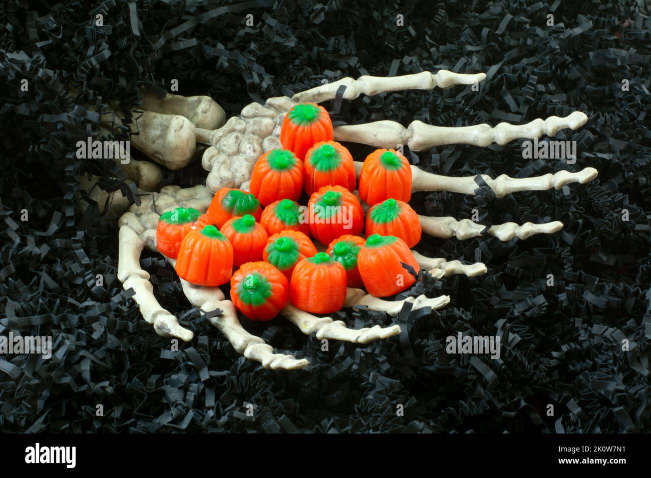 Haunted Haus knöchernen Skelett Hände aus schwarzem zerkratztem Papier halten Halloween Party Kürbis Süßigkeiten Stockfoto