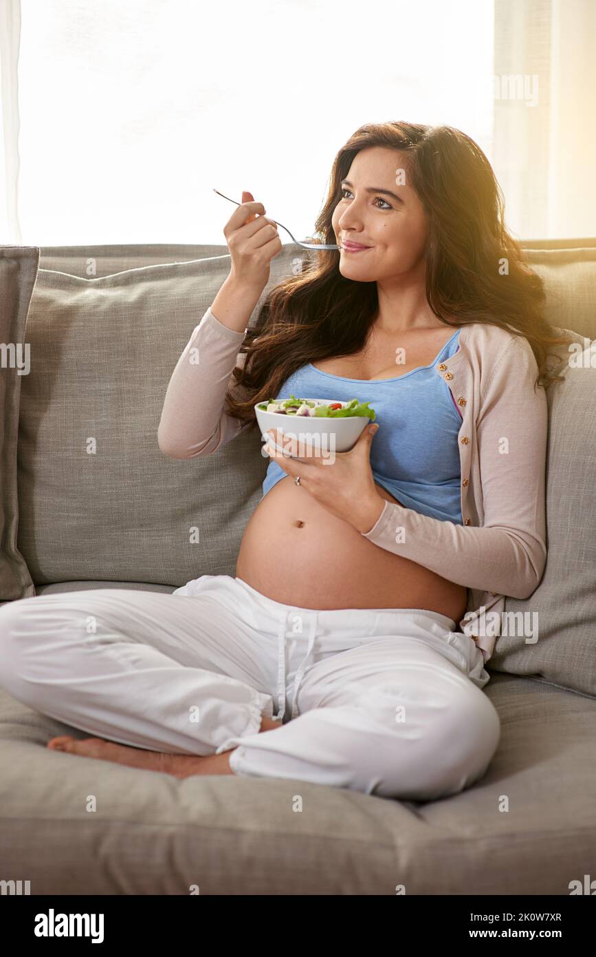 Gesunde Mutter, gesundes Baby. Eine Schwangerin, die zu Hause einen gesunden Salat isst. Stockfoto