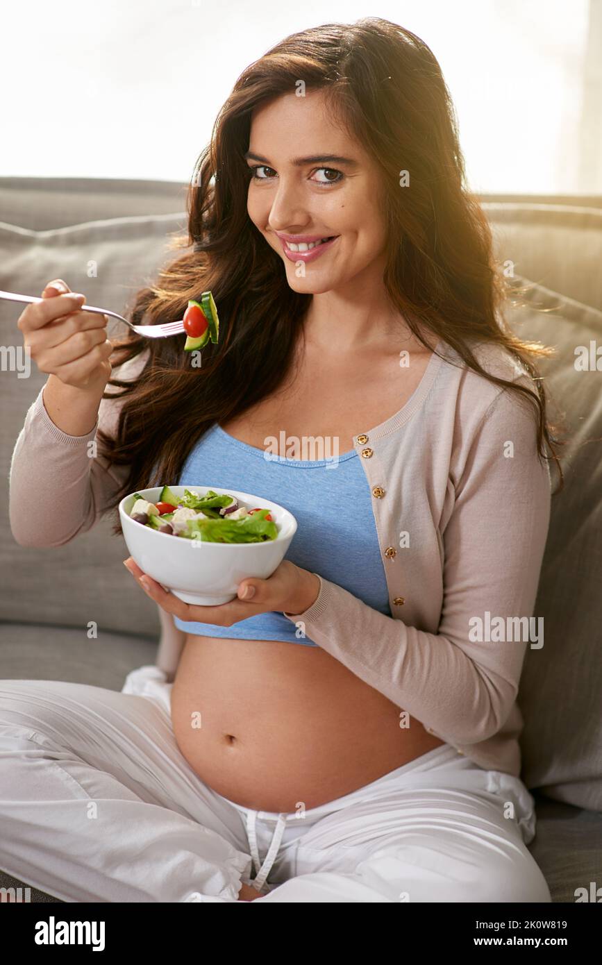 Mein Baby liebt es, wenn ich Bio-Lebensmittel esse. Eine Schwangere, die zu Hause einen gesunden Salat isst. Stockfoto