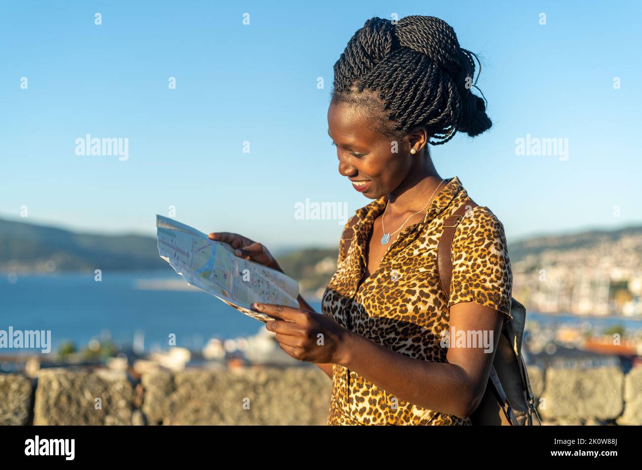 Junge Touristenfrau beim Betrachten einer Karte in einer Küstenstadt in Spanien, die eine europäische Stadt besucht Stockfoto