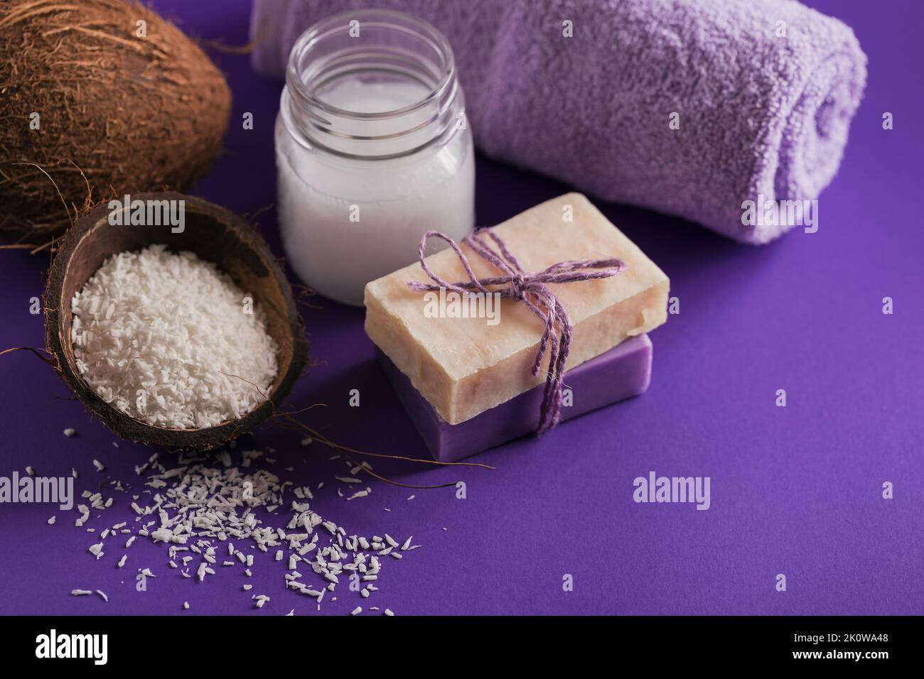 Bio Kokosöl und natürliche handgemachte Seife mit Kokosnuss auf violettem Hintergrund Stockfoto