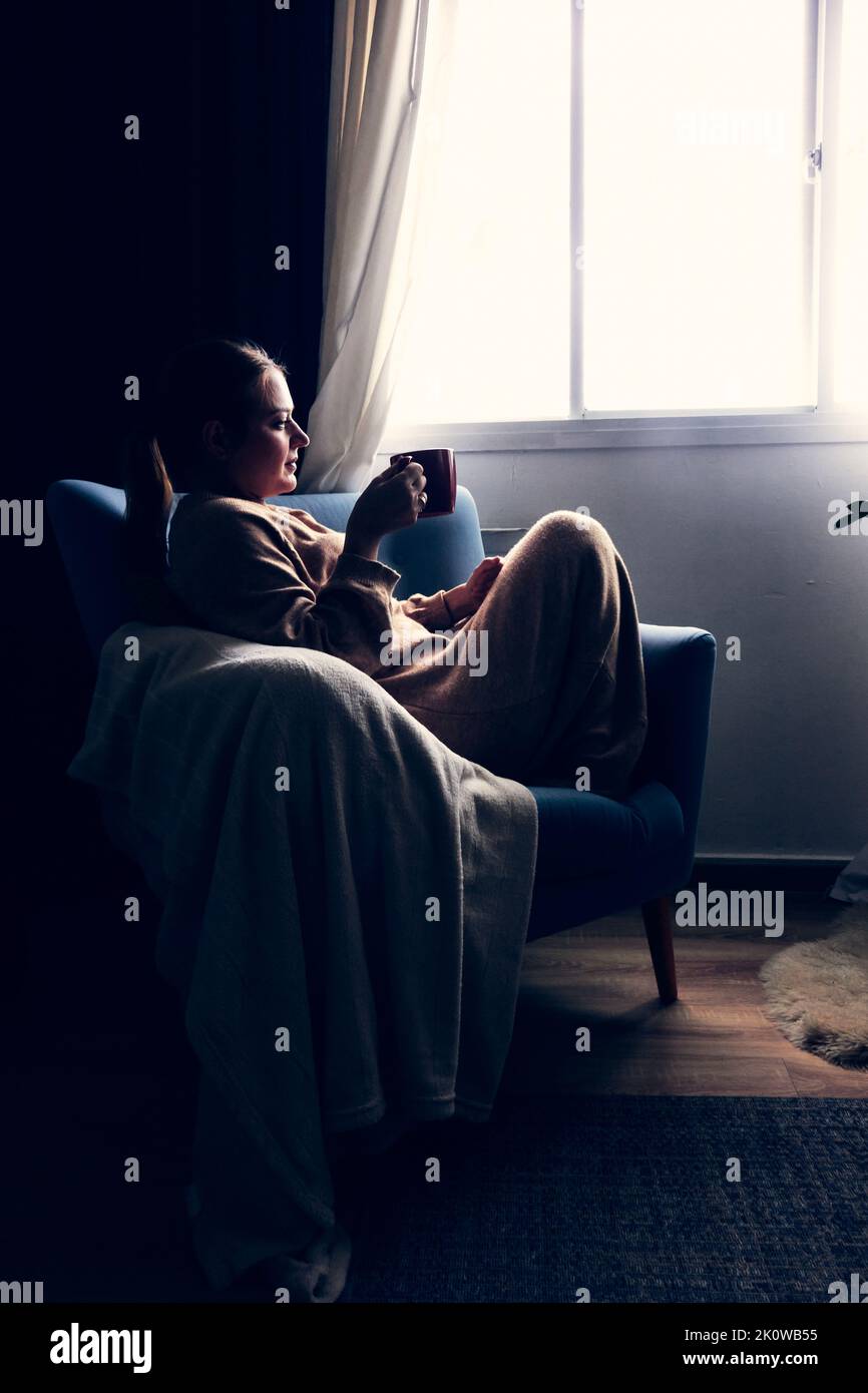 Junge Dame, die auf der Couch sitzt und Kaffee trinkt Stockfoto