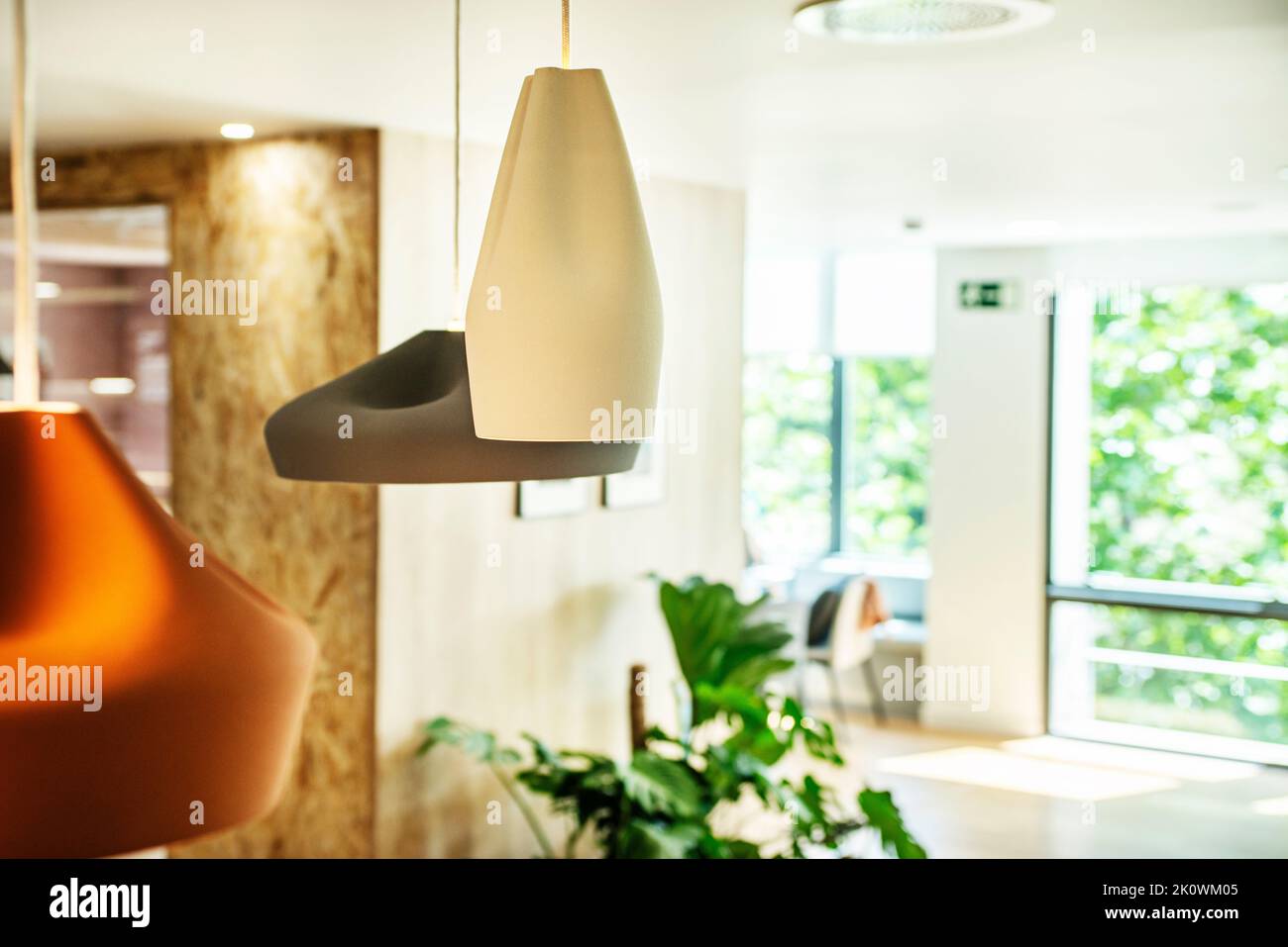 Designlampen, die in einem Büro mit großen Fenstern von der Decke hängen Stockfoto