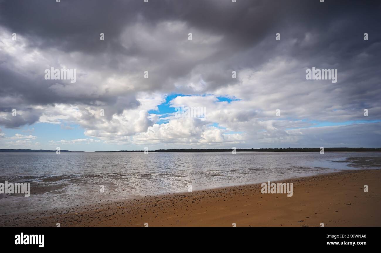 Drohende Regenwolken bilden sich über der Great Sandy Straits, Fraser Coast, Poona, Queensland. Schlammflatten zeigen sich, wenn die Flut ausläuft. Stockfoto