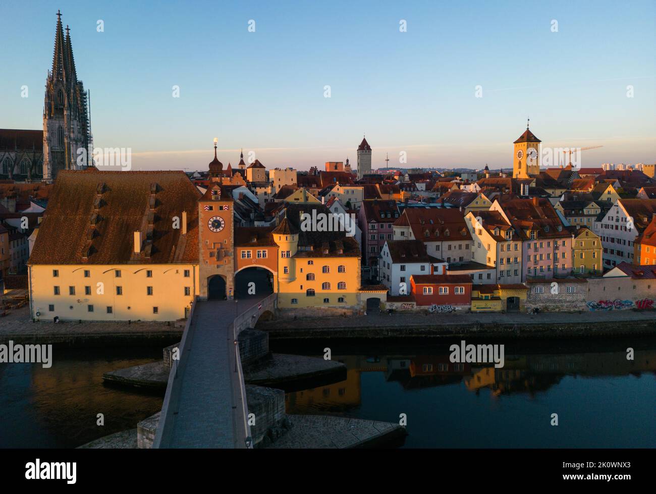 Regensburg, Deutschland. Eine Drohnenaufnahme der alten Steinbrücke, des Bruckturms, des Petersdoms und anderer Gebäude im alten Stadtzentrum bei Sonnenaufgang Stockfoto