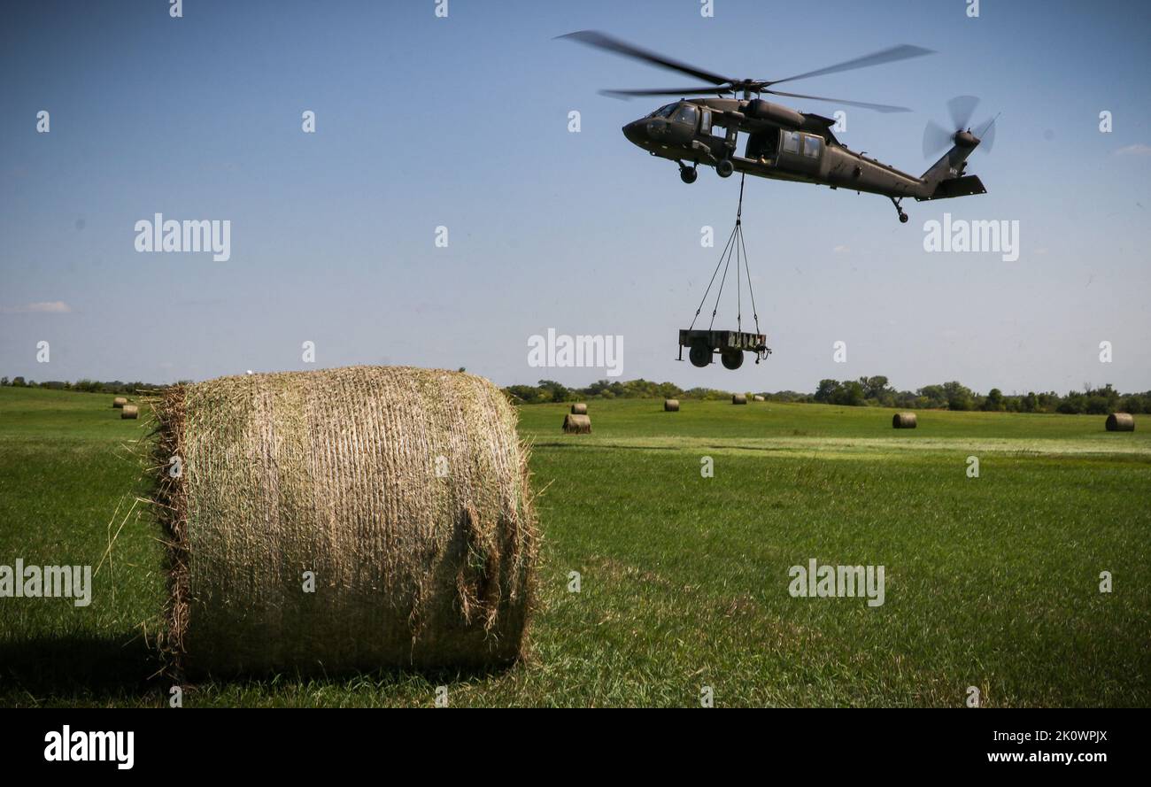 Ein Feld von Heuballen umrahmt eine Iowa Army National Guard UH-60 Black Hawk, während es einen Anhänger während eines U.S. Pathfinder Kurses im Camp Dodge in Johnston, Iowa, am 8. September 2022 belädt. Fast 30 Soldaten absolvierten den Kurs, der von einem mobilen Trainingsteam im Warrior Training Center der Army National Guard in Fort Benning, Georgia, unterrichtet wurde. Army Pathfinders werden geschult, um Navigationshilfe und Beratungsdienste für Militärflugzeuge in Gebieten zu leisten, die von unterstützten Einheiten-Kommandeuren bestimmt werden. Während des Pathfinder-Kurses werden die Studenten in der Flugzeugorientierung, der aerodynamischen Evakuierung, c Stockfoto