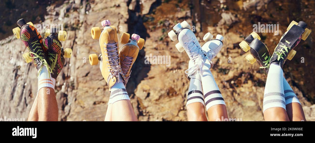 Rollschuhe, Spaß und Abenteuer Reisen mit Freunden Gruppe heben Beine und zeigen Retro-Skating Schuhe, während draußen. Gruppe von Frauen genießen Stockfoto