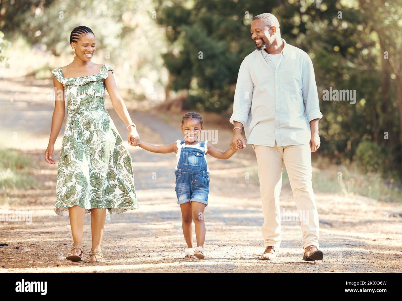 Schwarze Familie, liebe und aktive Eltern, die mit ihrem Kind durch die Natur spazieren, um Abenteuer und Spaß im Freien zu erleben. Glücklicher afrikanischer Mann und Frau mit Stockfoto