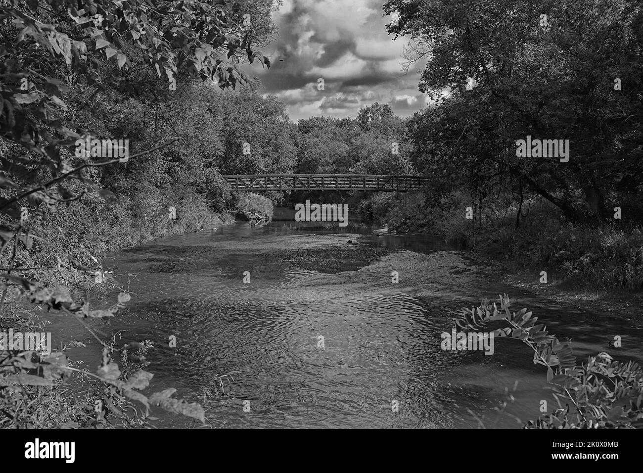 An einem bewölkten Abend ging ich an einer alten Brücke vorbei, die mit den feurigen Herbsttönen geschmückt war. Ich konnte der Schönheit der Szene nicht widerstehen. Stockfoto