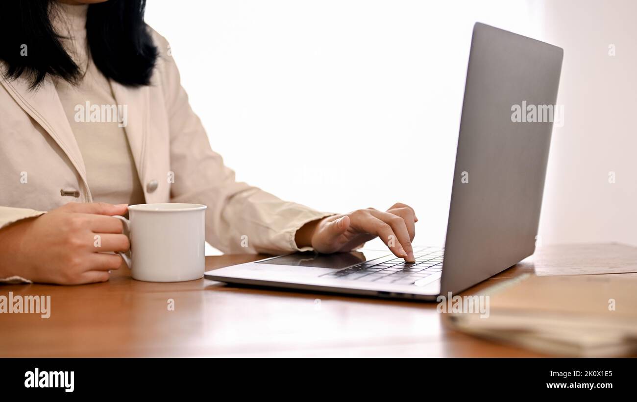 Abgeschnitten und Nahaufnahme Bild, Eine erfolgreiche asiatische Geschäftsfrau arbeitet an ihren geschäftlichen Aufgaben auf Notebook-Laptop-Computer. Stockfoto