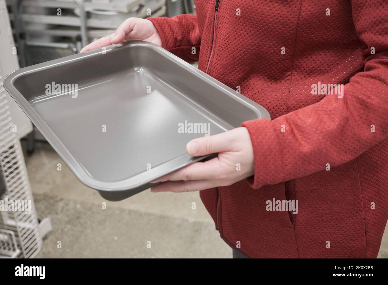 Kaukasisches Mädchen wählt eine Antihaft-Kuchenform im Laden. Nahaufnahme der Hände Stockfoto