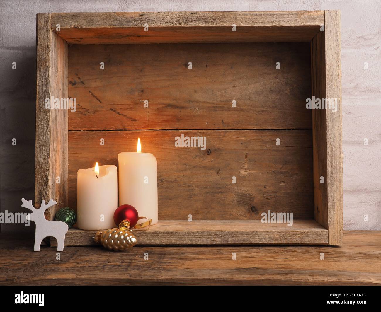Weiße Adventskerzen in einer Holzkiste mit weihnachtlicher Dekoration und Platz für Text Stockfoto