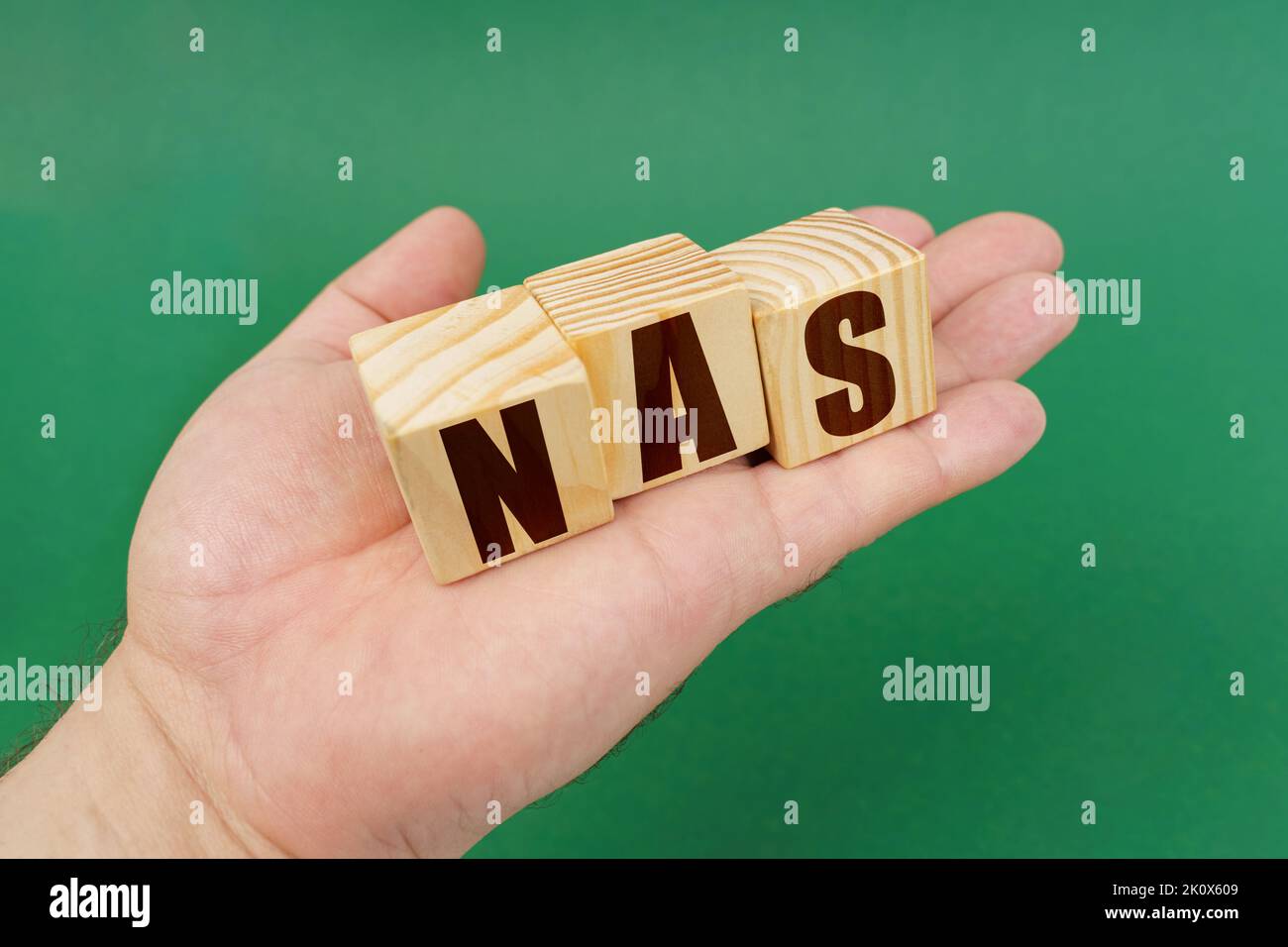 Geschäftskonzept. Auf einem grünen Hintergrund, in den Händen einer Person, Würfel mit der Aufschrift - NAS Stockfoto