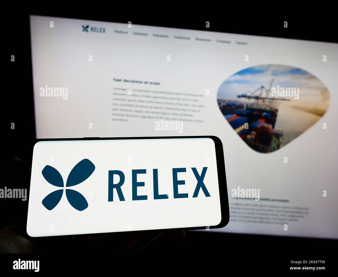 Person, die das Mobiltelefon mit dem Logo des finnischen Softwareunternehmens RELEX Solutions auf dem Bildschirm vor der Business-Webseite hält. Konzentrieren Sie sich auf die Telefonanzeige. Stockfoto